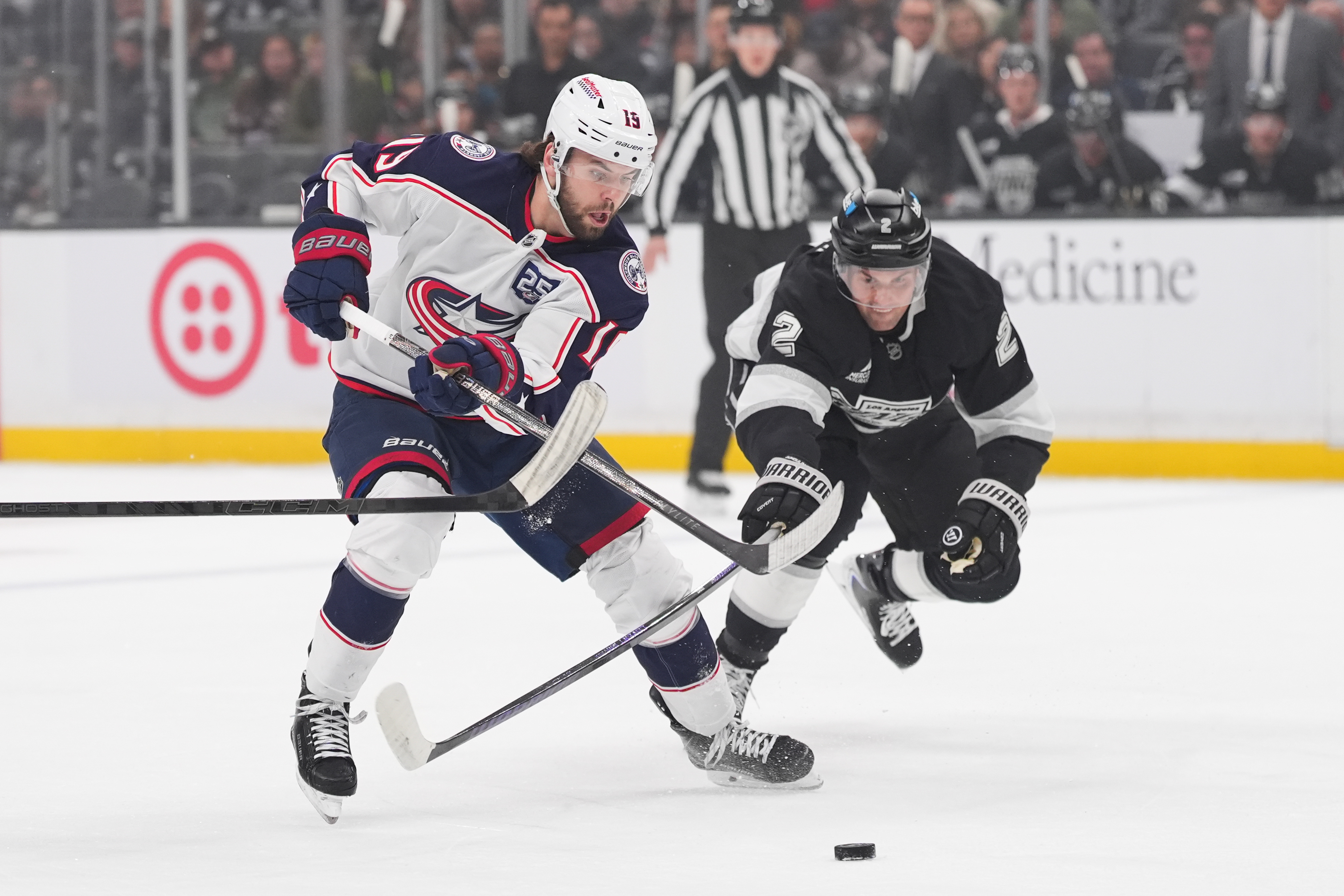 Columbus Blue Jackets defenseman Dante Fabbro, left, moves the puck...