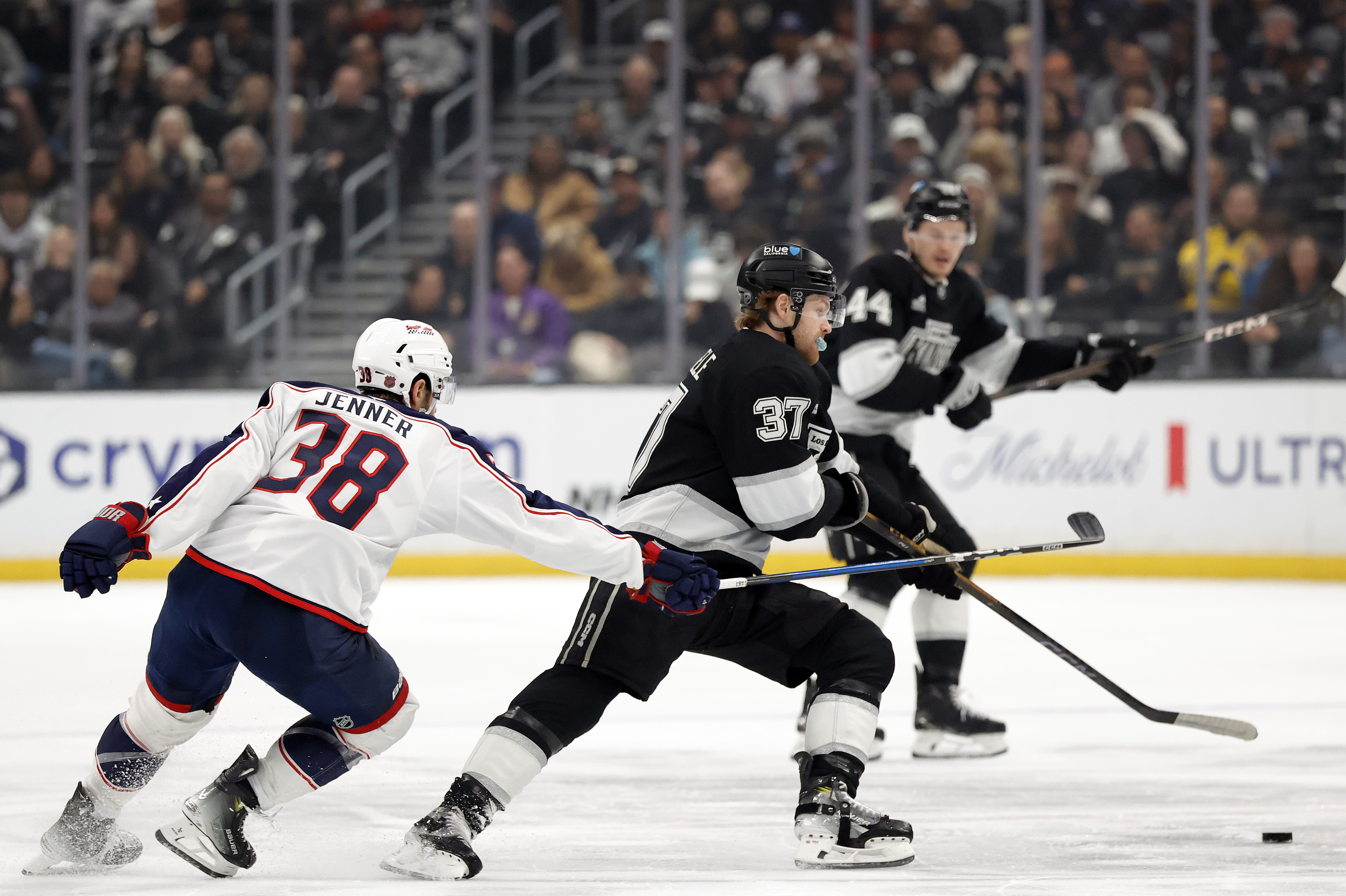 The Kings’ Warren Foegele, right, skates with the puck as...