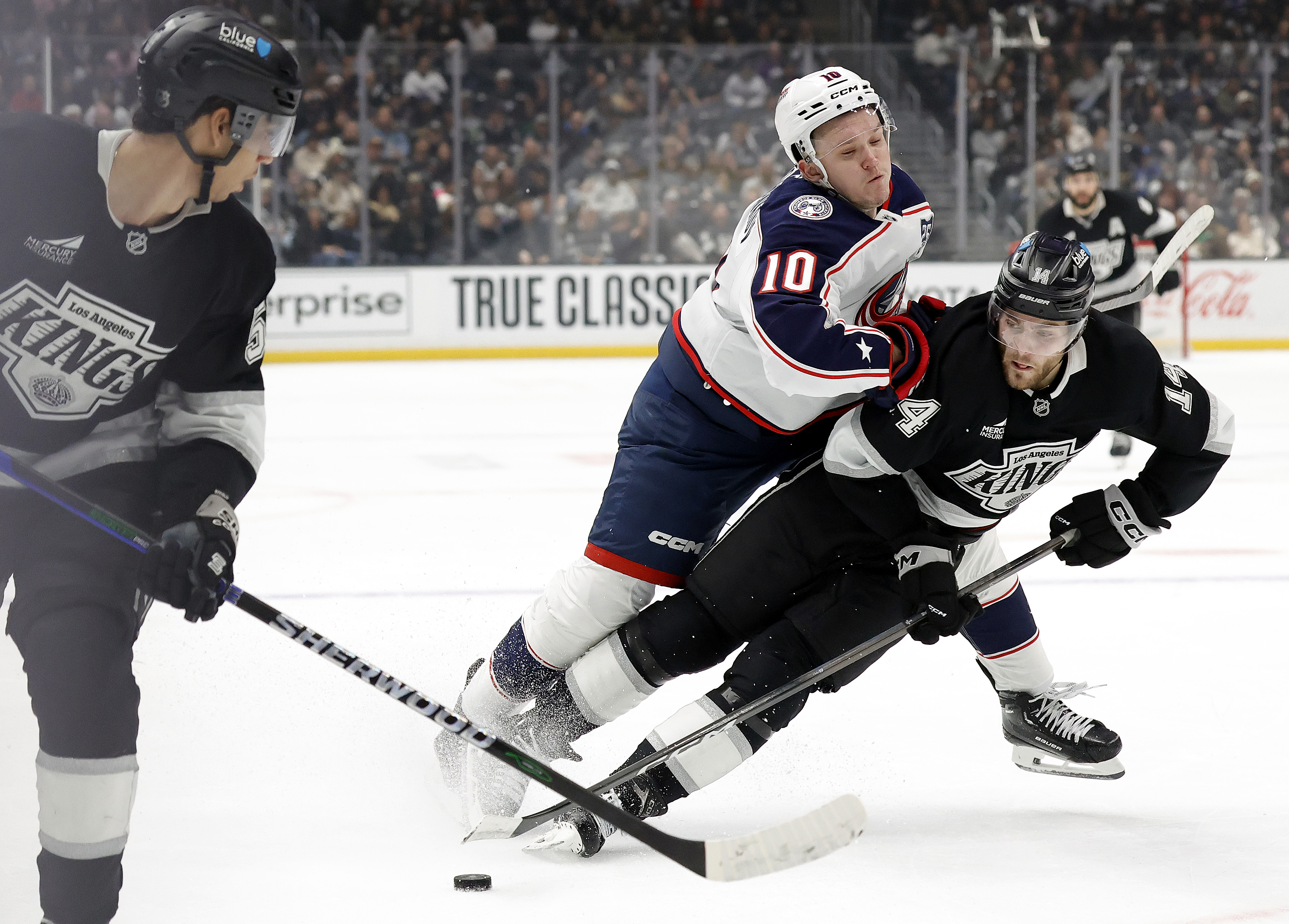 The Kings’ Alex Laferriere, right, skates with the puck against...