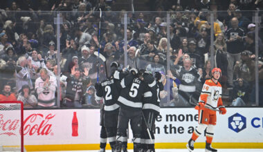 Los Angeles Kings left wing Trevor Moore (12), right, celebrates with Los Angeles Kings defenseman Brian Dumoulin (2), left, Los Angeles Kings defenseman Cody Ceci (5), center, and additional teammates after scoring a goal during the first period of an NHL hockey game against the Anaheim Ducks, Saturday, Dec. 27, 2025, in Los Angeles. (AP Photo/Katie Chin)
