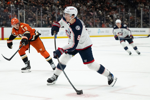 Columbus Blue Jackets defenseman Zach Werenski (8) shoots as Anaheim Ducks right wing Troy Terry (19) defends during the second period of an NHL hockey game, Saturday, Dec. 20, 2025, in Anaheim, Calif. (AP Photo/Kyusung Gong)