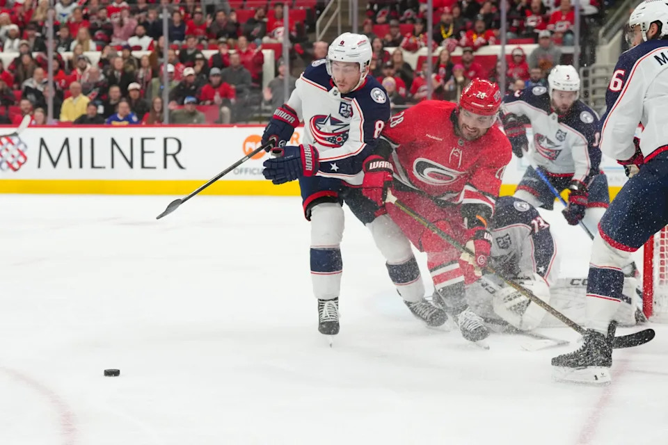Dec 9, 2025; Raleigh, North Carolina, USA; Carolina Hurricanes left wing William Carrier (28) and Columbus Blue Jackets defenseman Zach Werenski (8) battle over the puck during the third period at Lenovo Center. Mandatory Credit: James Guillory-Imagn Images