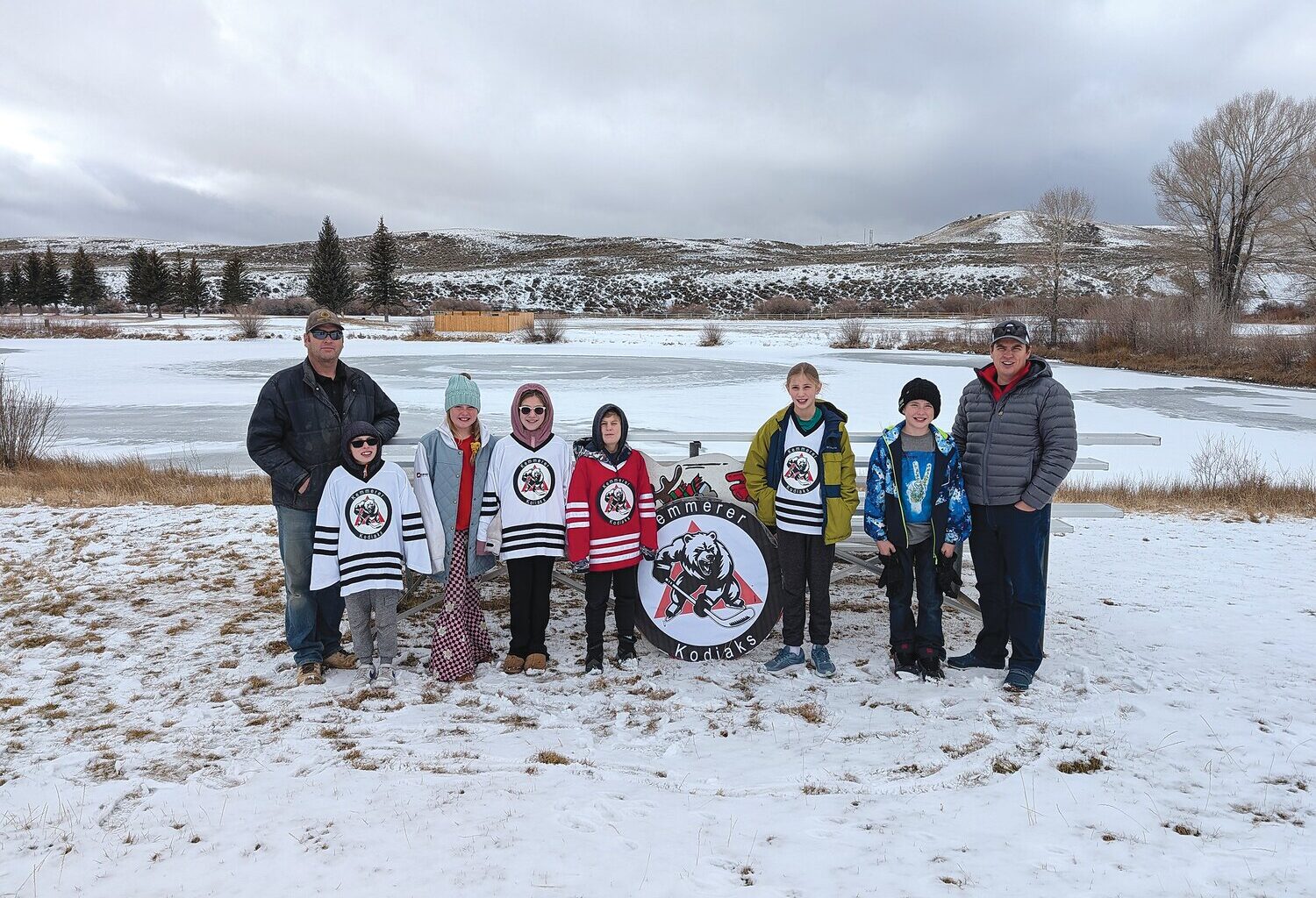 Kemmerer Mayor Robert Bowen and some members of the Kemmerer Hockey League stand near the bleachers with the pond in the background. Pictured are Mayor Bowen, Preston Nelson, Maddox Seamon, Paizlee Nelson, Graham Calkins, Beth Calkins, Grayson Seamon and Adam Calkins.