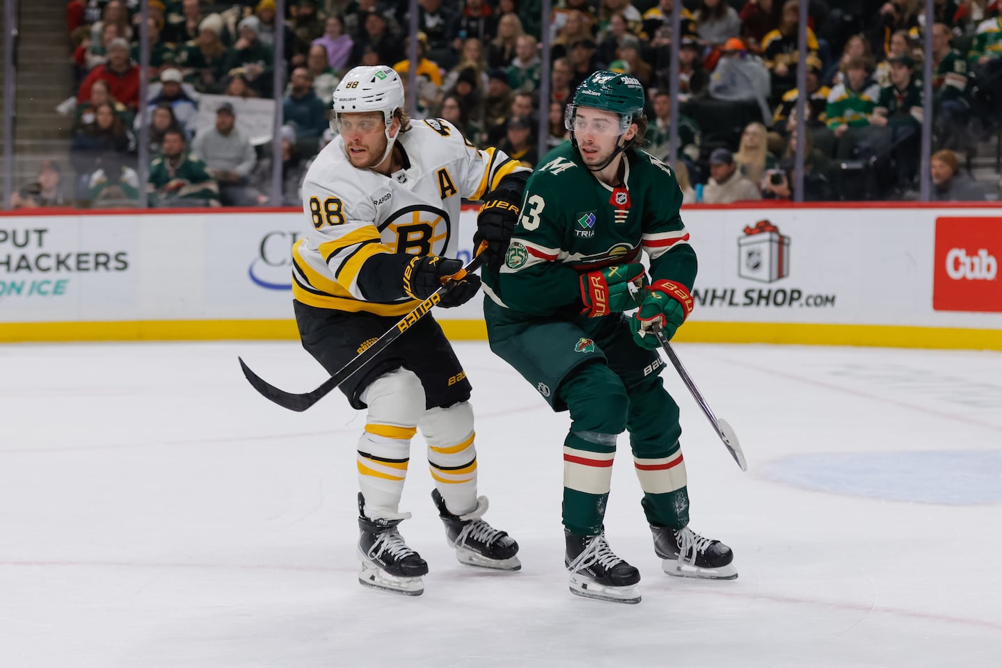 David Pastrnak battles with the Wild's new superstar, Quinn Hughes, in Sunday's Bruins loss in Minnesota.