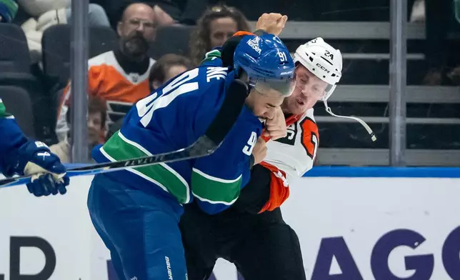 Vancouver Canucks' Evander Kane (91) and Philadelphia Flyers' Nick Seeler (24) fight during the first period of an NHL game in Vancouver, Tuesday, Dec. 30, 2025. (Ethan Cairns/The Canadian Press via AP)