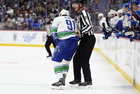 Dec 2, 2025; Denver, Colorado, USA;NHL linesman Travis Toomey (90) assists Vancouver Canucks left wing Evander Kane (91) leaves the ice due to an injury during the third period against the Colorado Avalanche at Ball Arena.