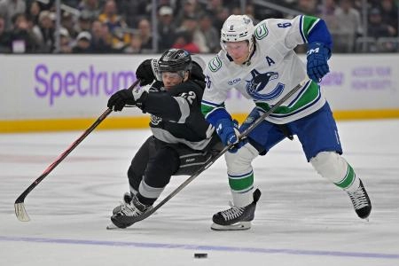 Nov 29, 2025; Los Angeles, California, USA; Los Angeles Kings left wing Kevin Fiala (22) and Vancouver Canucks right wing Brock Boeser (6) battle for the puck during the overtime period at Crypto.com Arena.