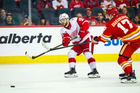 Dec 10, 2025; Calgary, Alberta, CAN; Detroit Red Wings right wing Alex Debrincat (93) passes the puck against Calgary Flames center Yegor Sharangovich (17) during the first period at Scotiabank Saddledome.
