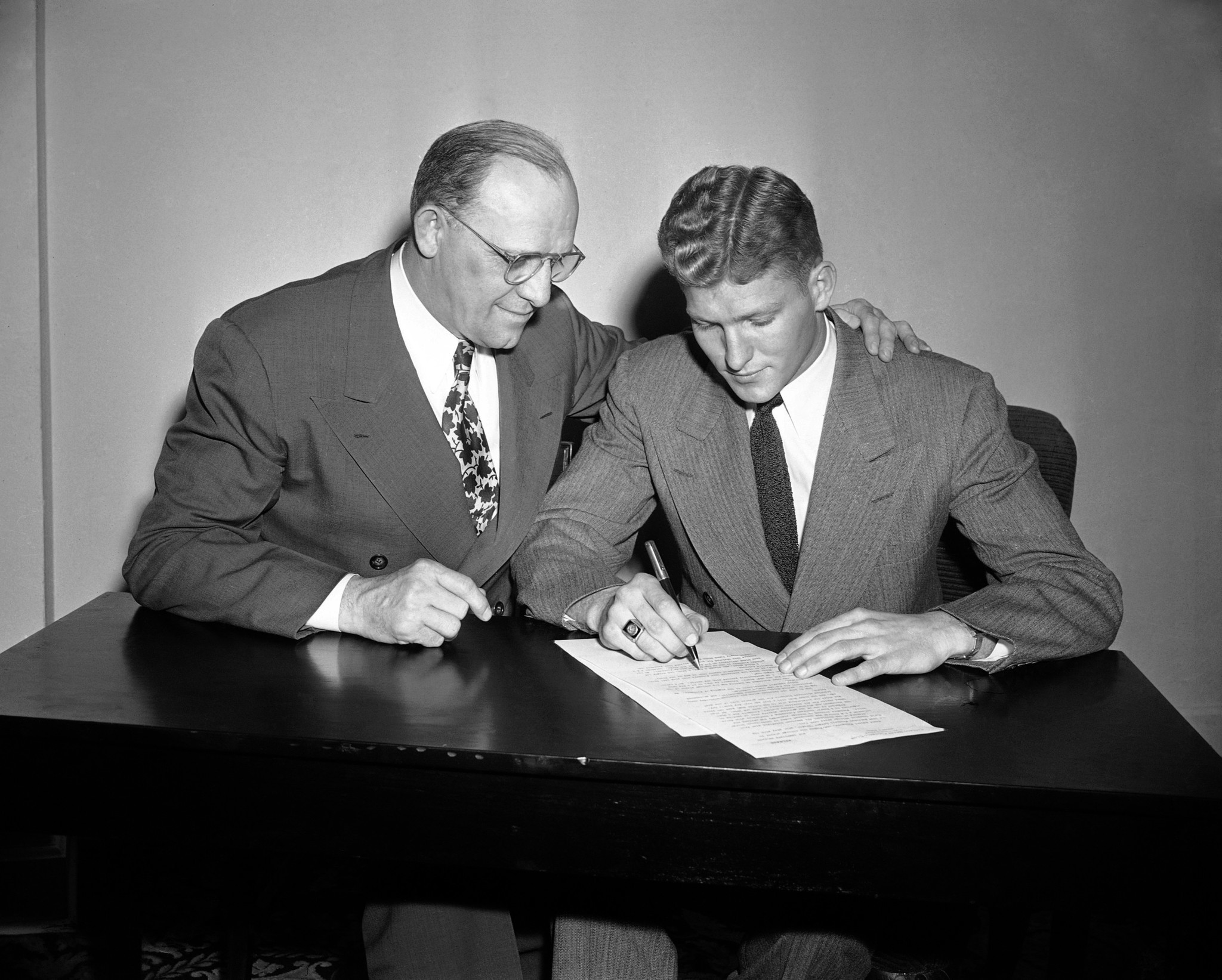 Bears owner and coach George Halas, left, watches as Bob Fenimore signs a contract with the team on Jan. 18, 1947.