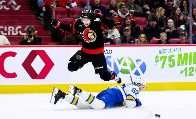 Ottawa Senators' Ridly Greig (71) leaps over St. Louis Blues' Jake Neighbours (63) as he makes a pass during second-period NHL hockey game action in Ottawa, Ontario, Saturday, Dec. 6, 2025. (Spencer Colby/The Canadian Press via AP)