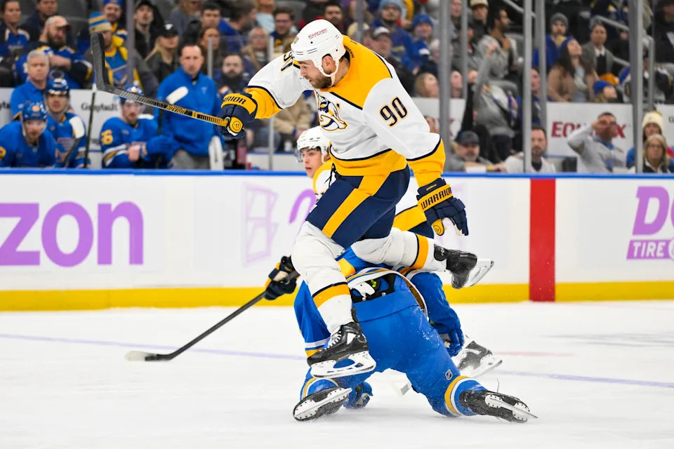 Dec 15, 2025; St. Louis, Missouri, USA; Nashville Predators center Ryan O'Reilly (90) leaps over St. Louis Blues center Robby Fabbri (9) during the third period at Enterprise Center. Mandatory Credit: Jeff Curry-Imagn Images
