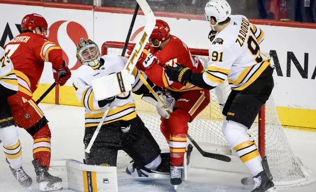 Boston Bruins' Nikita Zadorov, right, checks Calgary Flames' Nazem Kadri, centre, into goalie Jeremy Swayman during second period NHL hockey action in Calgary on Monday, Dec. 29, 2025. (Jeff McIntosh/The Canadian Press via AP)