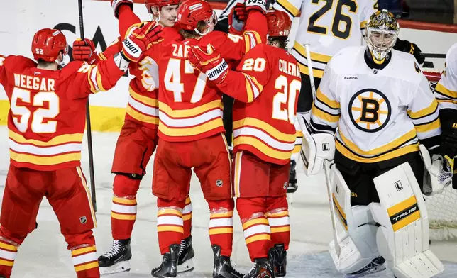 Boston Bruins goalie Jeremy Swayman, right, skates away as Calgary Flames players celebrate after winning in overtime NHL hockey game action in Calgary, Alberta, Monday, Dec. 29, 2025. (Jeff McIntosh/The Canadian Press via AP)