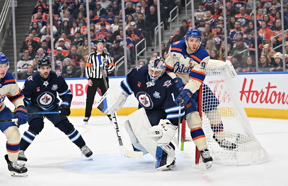 Edmonton Oilers center Connor McDavid (97) and Winnipeg Jets goalie Eric Comrie (1) collide during the first period at Rogers Place.Walter Tychnowicz-Imagn Images