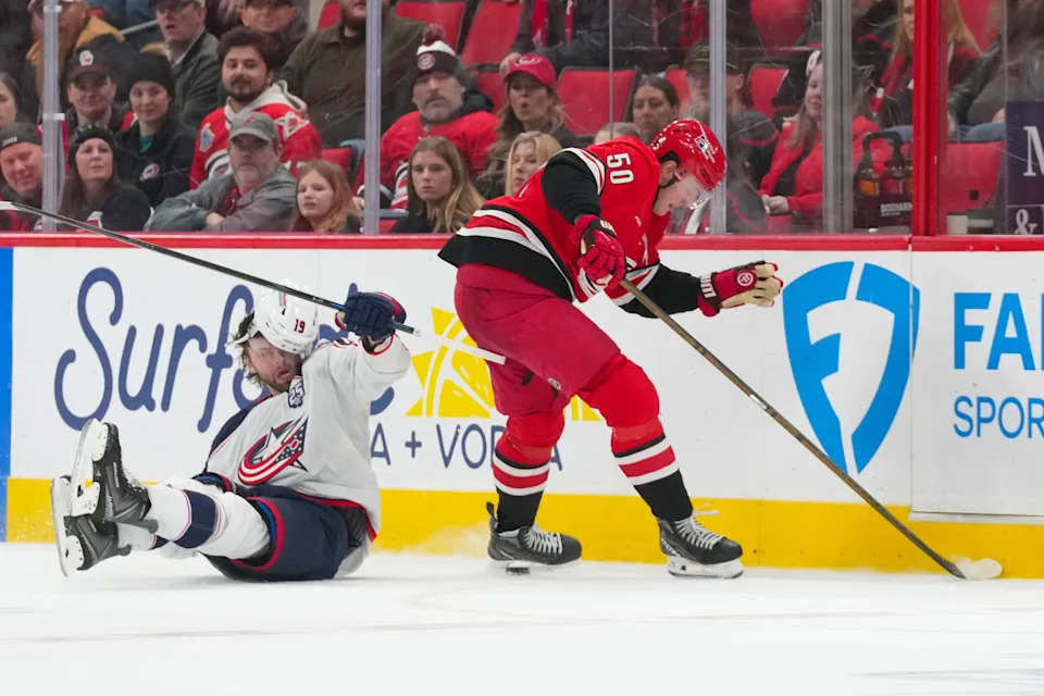 Dec 9, 2025; Raleigh, North Carolina, USA; Carolina Hurricanes left wing Eric Robinson (50) checks Columbus Blue Jackets defenseman Dante Fabbro (15) during the third period at Lenovo Center. Mandatory Credit: James Guillory-Imagn Images