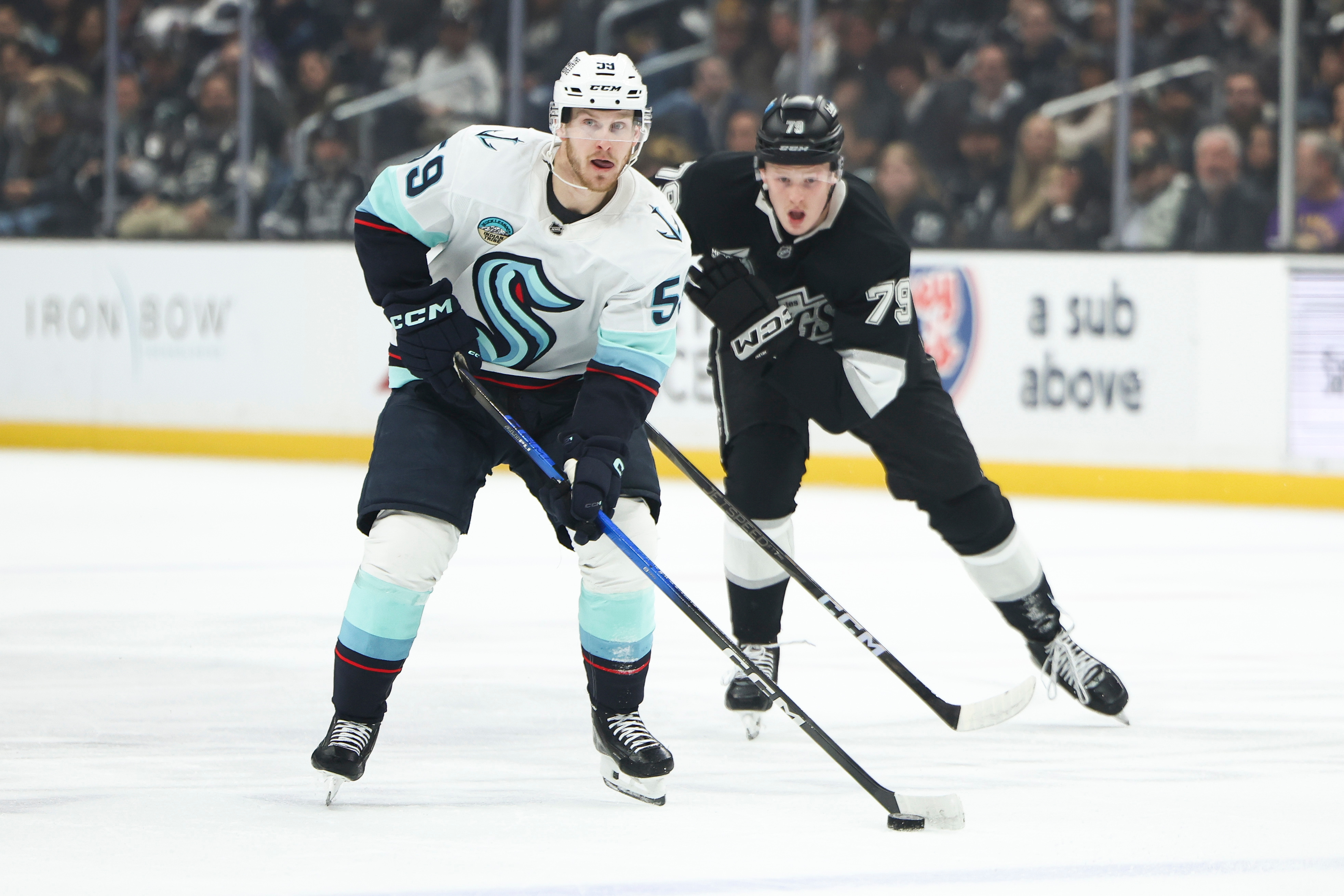 Seattle Kraken center Ben Meyers, front, skates with the puck...
