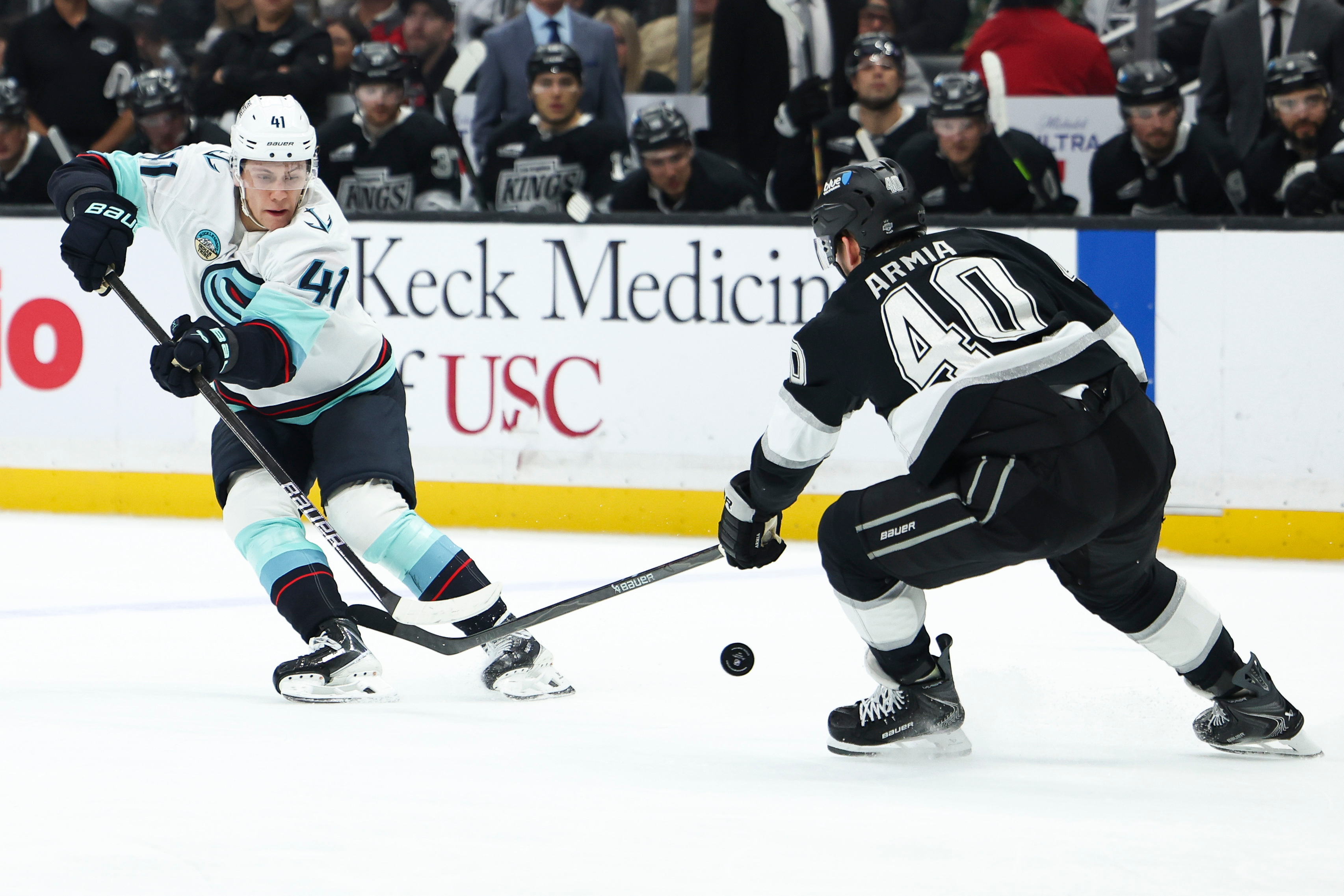 Seattle Kraken defenseman Ryker Evans, left, passes the puck as...