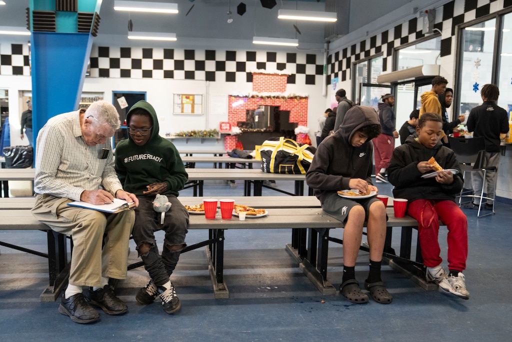 Noel Acton and Kyree Jones catch up while eating pizza with Baltimore Banner Hockey teammates and coaches at Mt. Pleasant Ice Arena, in Baltimore, Saturday, December 20, 2025.