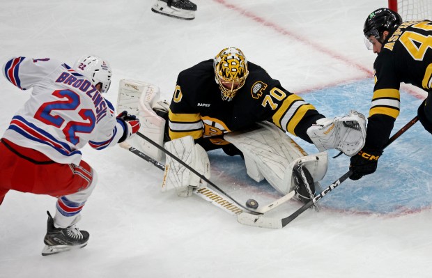 Boston Bruins goaltender Joonas Korpisalo (70) reaches to collect the puck as New York Rangers center Jonny Brodzinski digs for a rebound Friday afternoon. (Staff Photo By Stuart Cahill/Boston Herald)