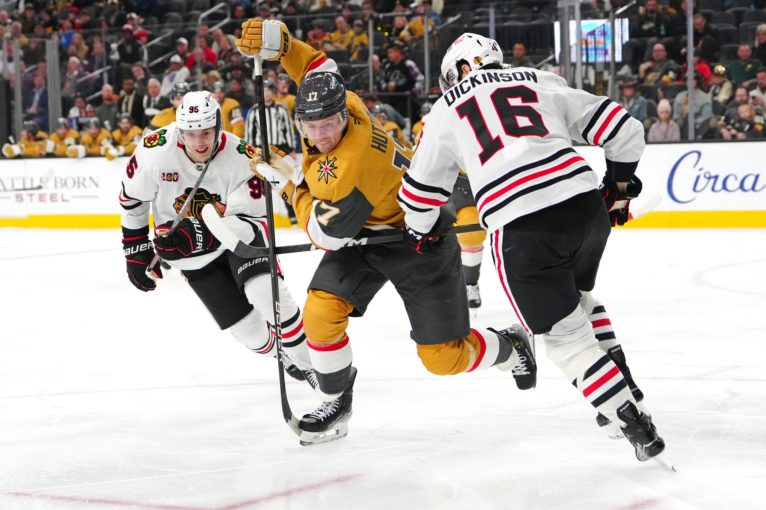 Dec 2, 2025; Las Vegas, Nevada, USA; Vegas Golden Knights defenseman Ben Hutton (17) skates between Chicago Blackhawks right wing Ilya Mikheyev (95) and center Jason Dickinson (16) during the third period at T-Mobile Arena.