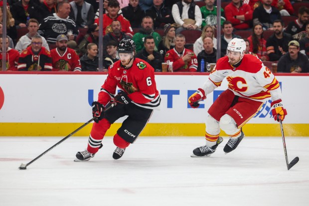Blackhawks defenseman Sam Rinzel (6) keeps the puck away from Flames right wing Adam Klapka (43) during the second period, Nov. 18, 2025, at the United Center. (Dominic Di Palermo/Chicago Tribune)