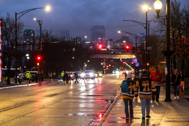 Clouds from today's rain linger over hockey fans walking near the United Center before a game between the Blackhawks and Pittsburgh Penguins, Dec. 28, 2025, at the United Center. (Dominic Di Palermo/Chicago Tribune)