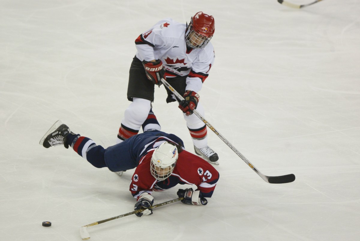 SALT LAKE CITY - FEBRUARY 21:  Forward Caroline Ouellette #13 of Canada knocks down forward Julie Chu #13 of the USA as she tries to play the puck during the womens ice hockey gold medal game on February 21, 2002 at the Salt Lake City Winter Olympic at the E Center in Salt Lake City, Utah. (Photo by Robert Laberge/Getty Images)