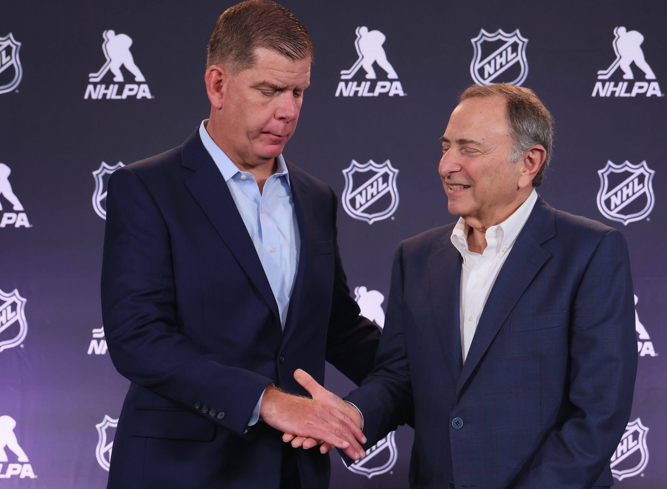 The NHLPA's Marty Walsh, left, shakes hands with NHL commissioner Gary Bettman.