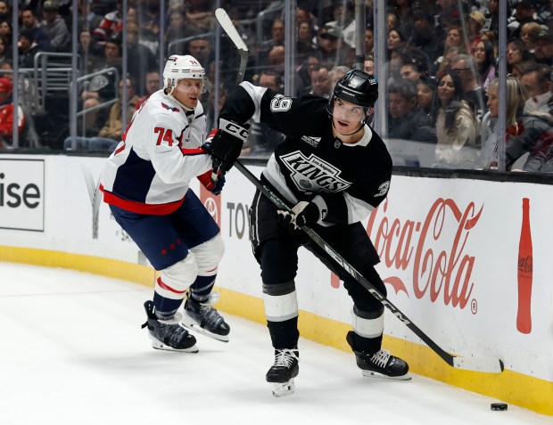 The Kings’ Jeff Malott, right, plays the puck in front...