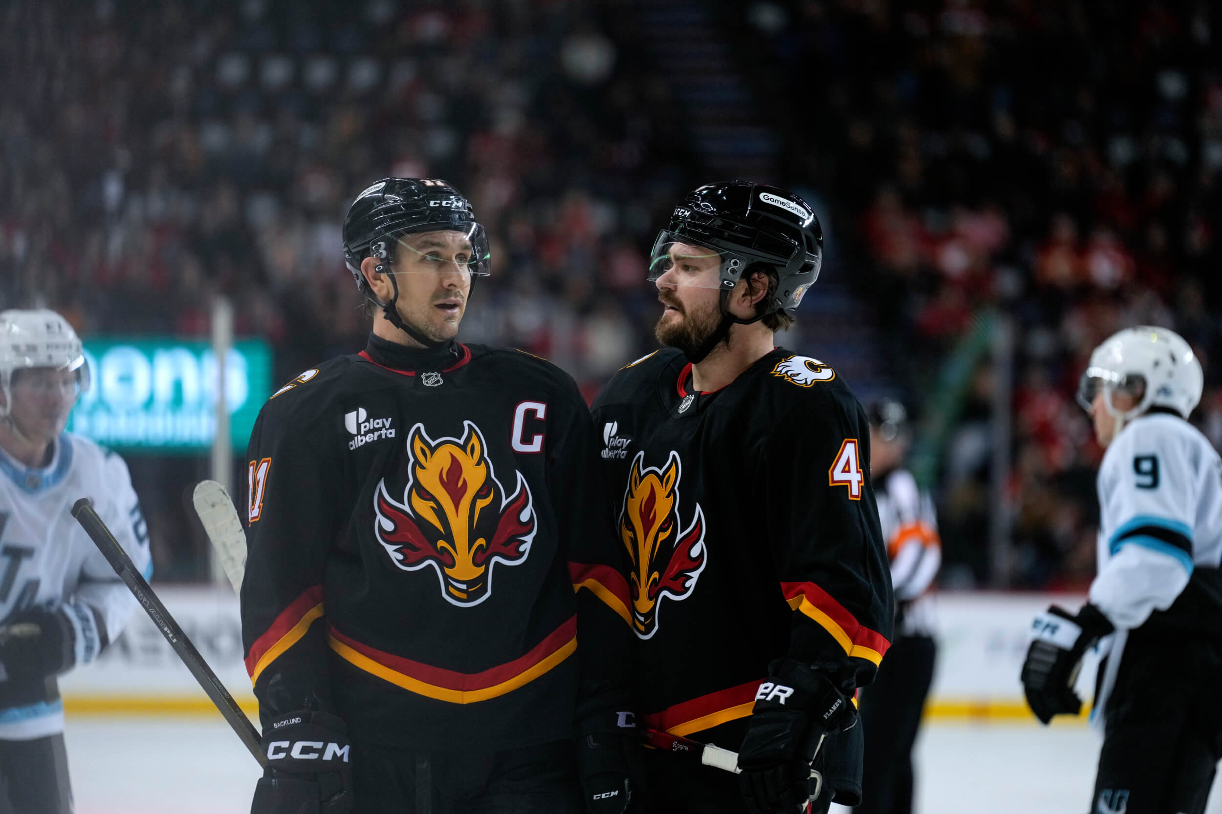 The Flames' Mikael Backlund and Rasmus Andersson talk during a stoppage of play against the Utah Mammoth.