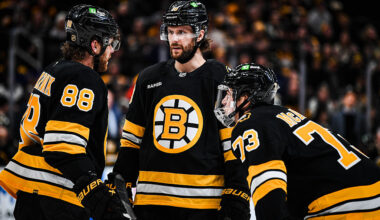 BOSTON, MASSACHUSETTS - DECEMBER 20: Pavel Zacha #18 of the Boston Bruins speaks with teammates David Pastrnak #88 and Charlie McAvoy #73 during over time against the Vancouver Canucks at TD Garden on December 20, 2025 in Boston, Massachusetts. (Photo by China Wong/NHLI via Getty Images)