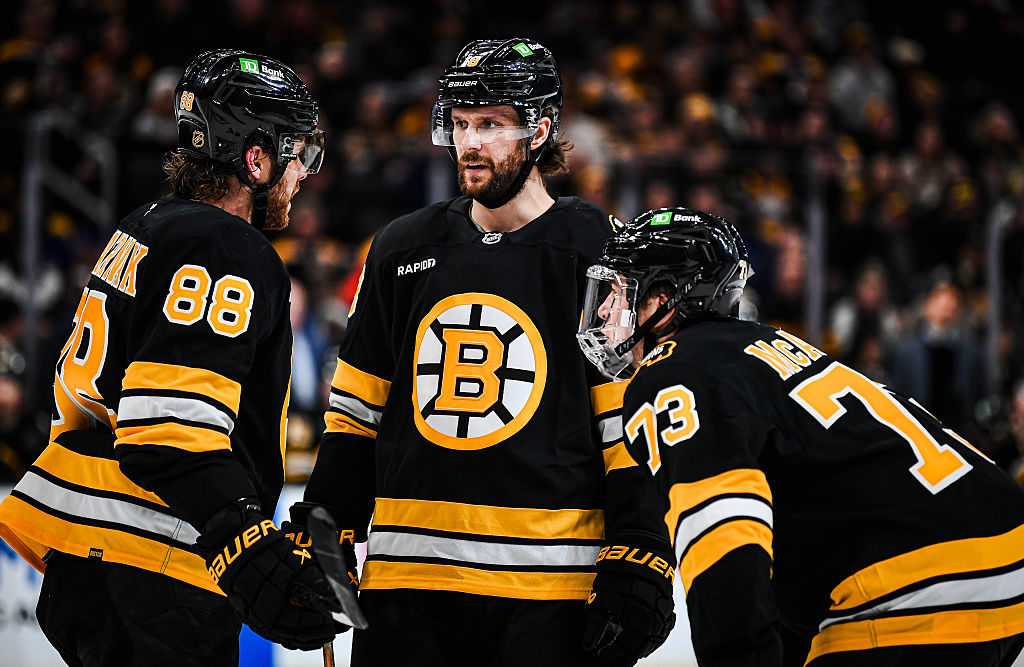 BOSTON, MASSACHUSETTS - DECEMBER 20: Pavel Zacha #18 of the Boston Bruins speaks with teammates David Pastrnak #88 and Charlie McAvoy #73 during over time against the Vancouver Canucks at TD Garden on December 20, 2025 in Boston, Massachusetts. (Photo by China Wong/NHLI via Getty Images)