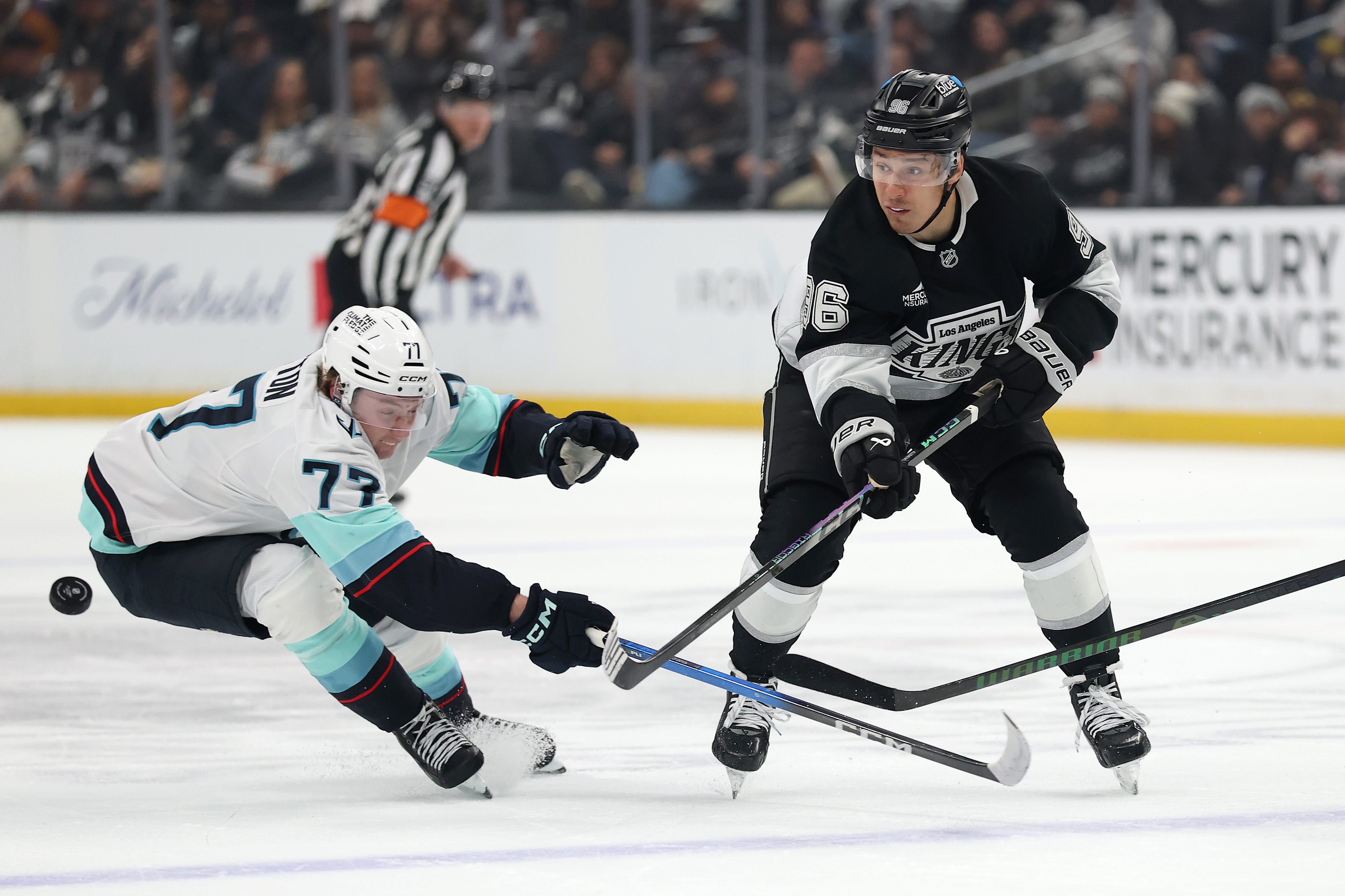 The Kings’ Andrei Kuzmenko, right, passes the puck as the...