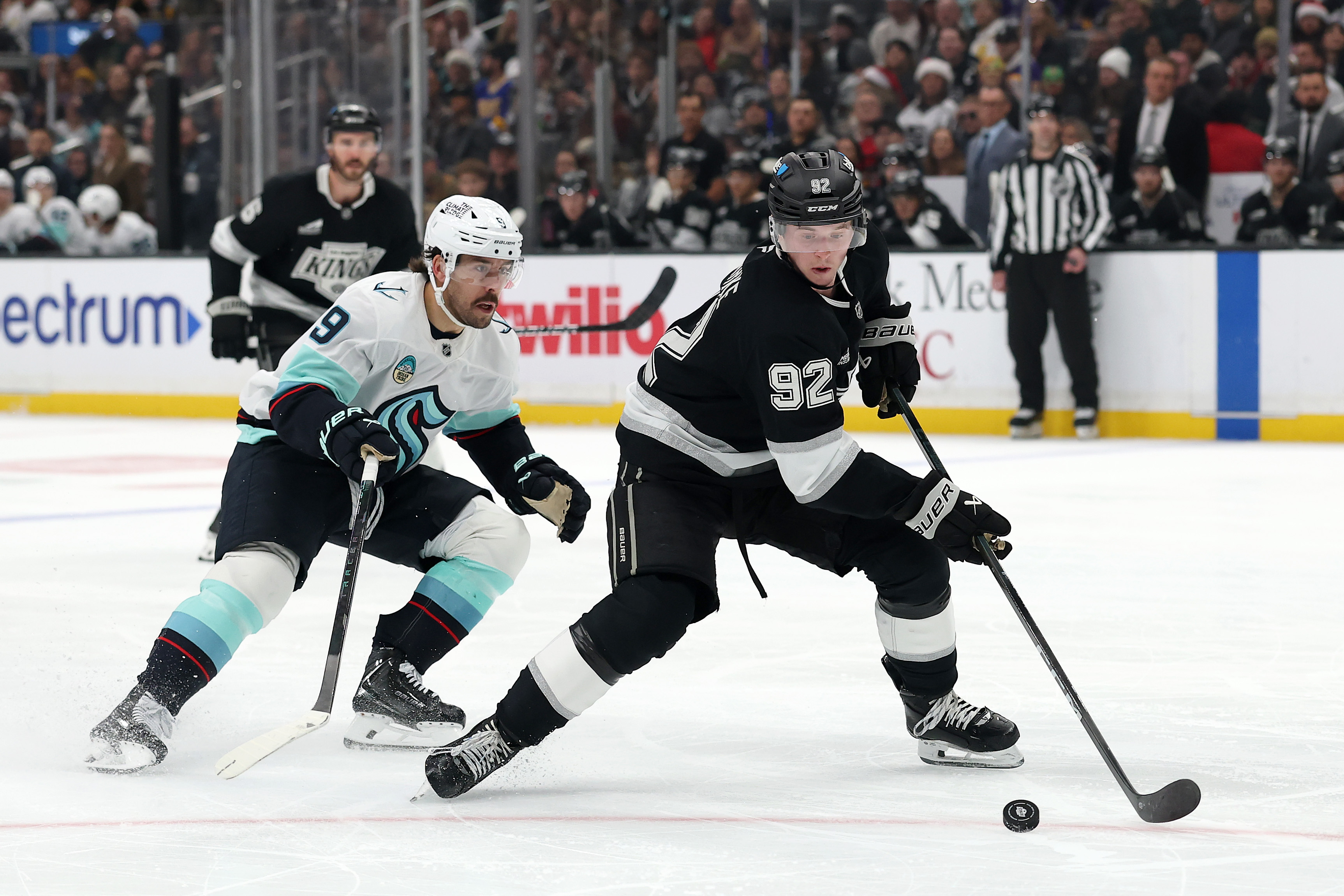 The Kings’ Brandt Clarke, right, skates with the puck as...