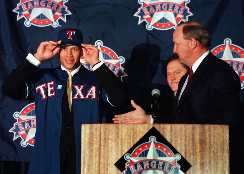 Texas Rangers new short stop Alex Rodriguez, left, tries on the team's ball cap after being...
