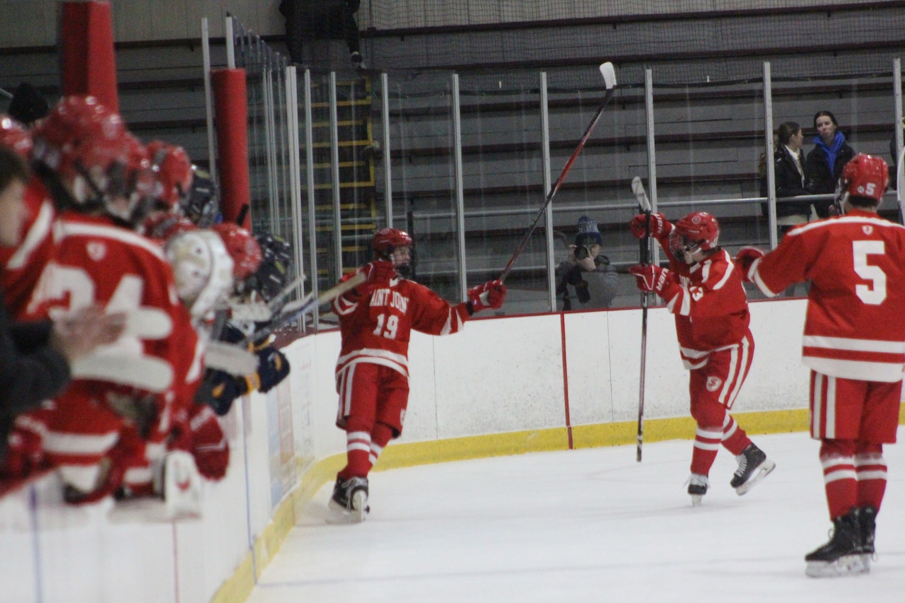 Jaydon Wrzosek celebrates scoring for Saint John's hockey against Arlington Catholic.