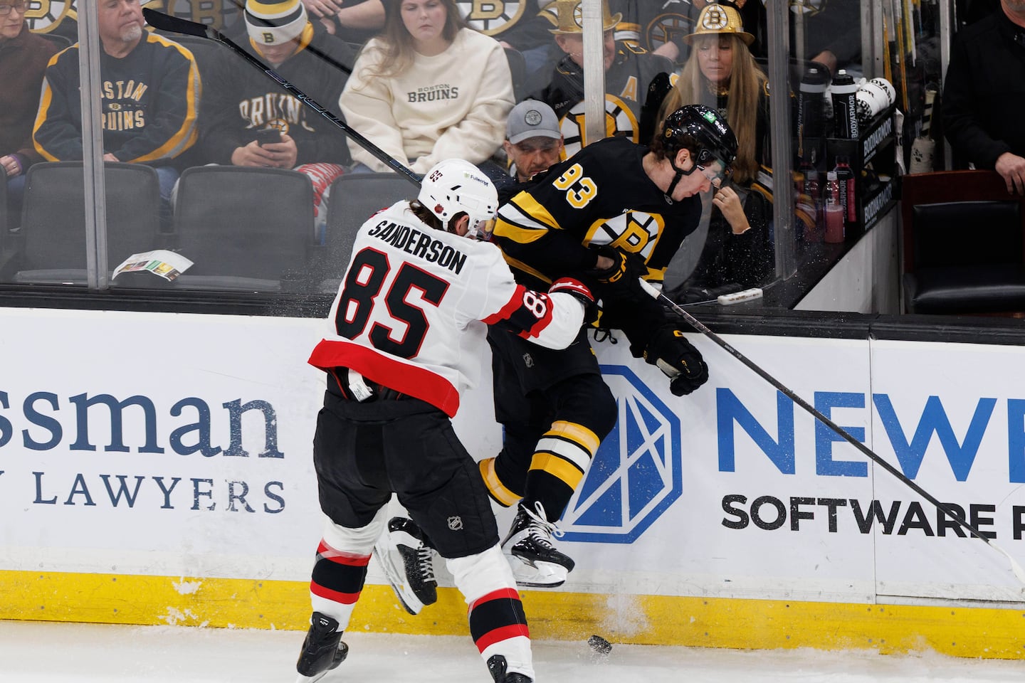Ottawa's Jake Sanderson (85) checks Bruins forward Fraser Minten hard into the boards Sunday. 