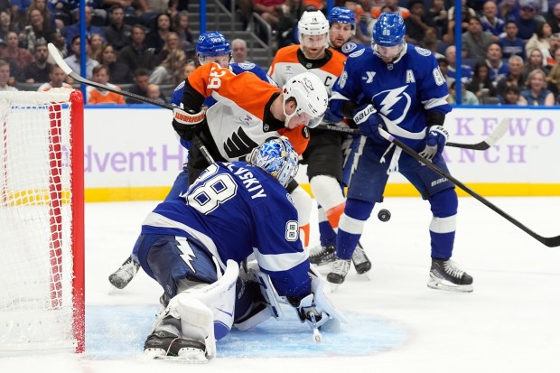Tampa Bay Lightning goaltender Andrei Vasilevskiy stops a shot by Philadelphia Flyers right wing Matvei Michkov as Lightning's right wing Nikita Kucherov (86) looks for the puck during the third period of an NHL hockey game Monday, Nov. 24, 2025, in Tampa, Fla. (AP Photo/Chris O'Meara)