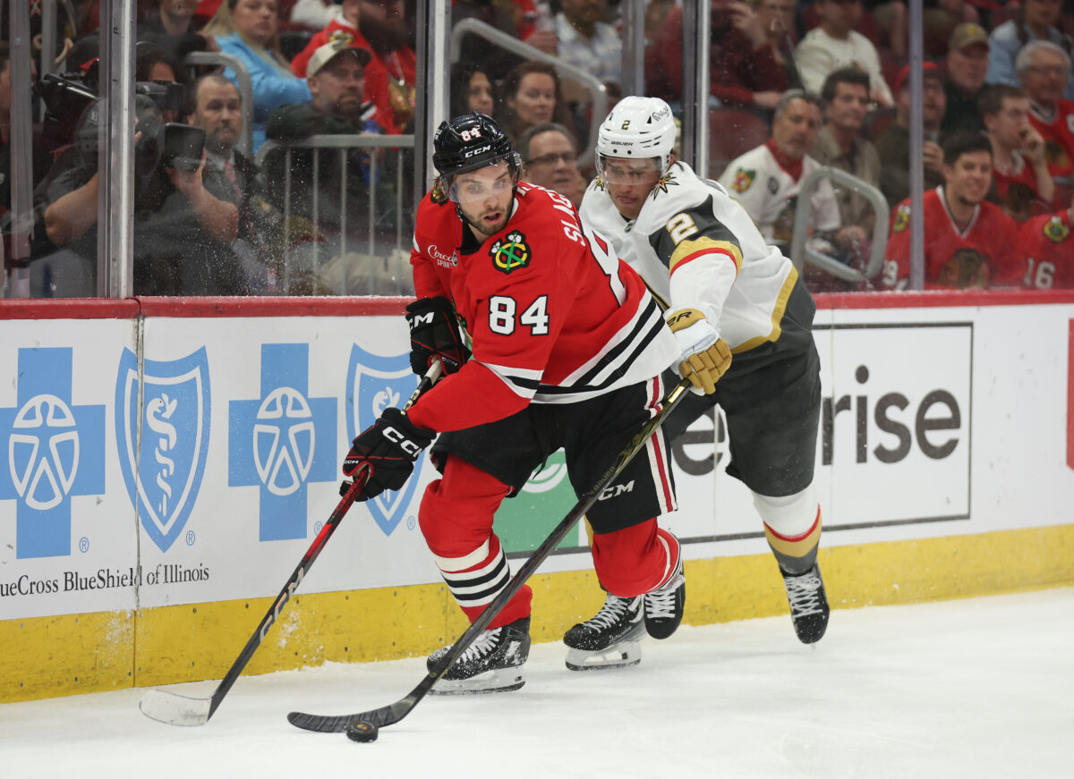 Mar 28, 2025; Chicago, Illinois, USA; Chicago Blackhawks left wing Landon Slaggert (84) and Vegas Golden Knights defenseman Zach Whitecloud (2) battle for control of the puck during the third period at United Center. Mandatory Credit: Talia Sprague-Imagn Images
