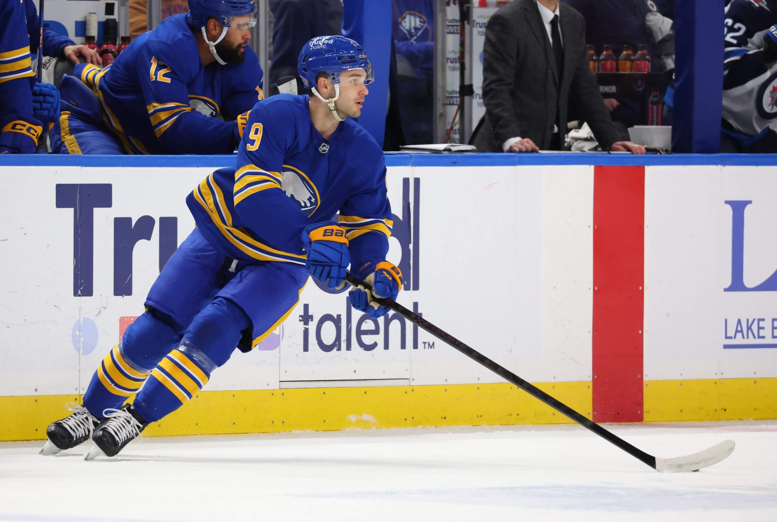 Josh Norris skates with the puck near the Buffalo bench.