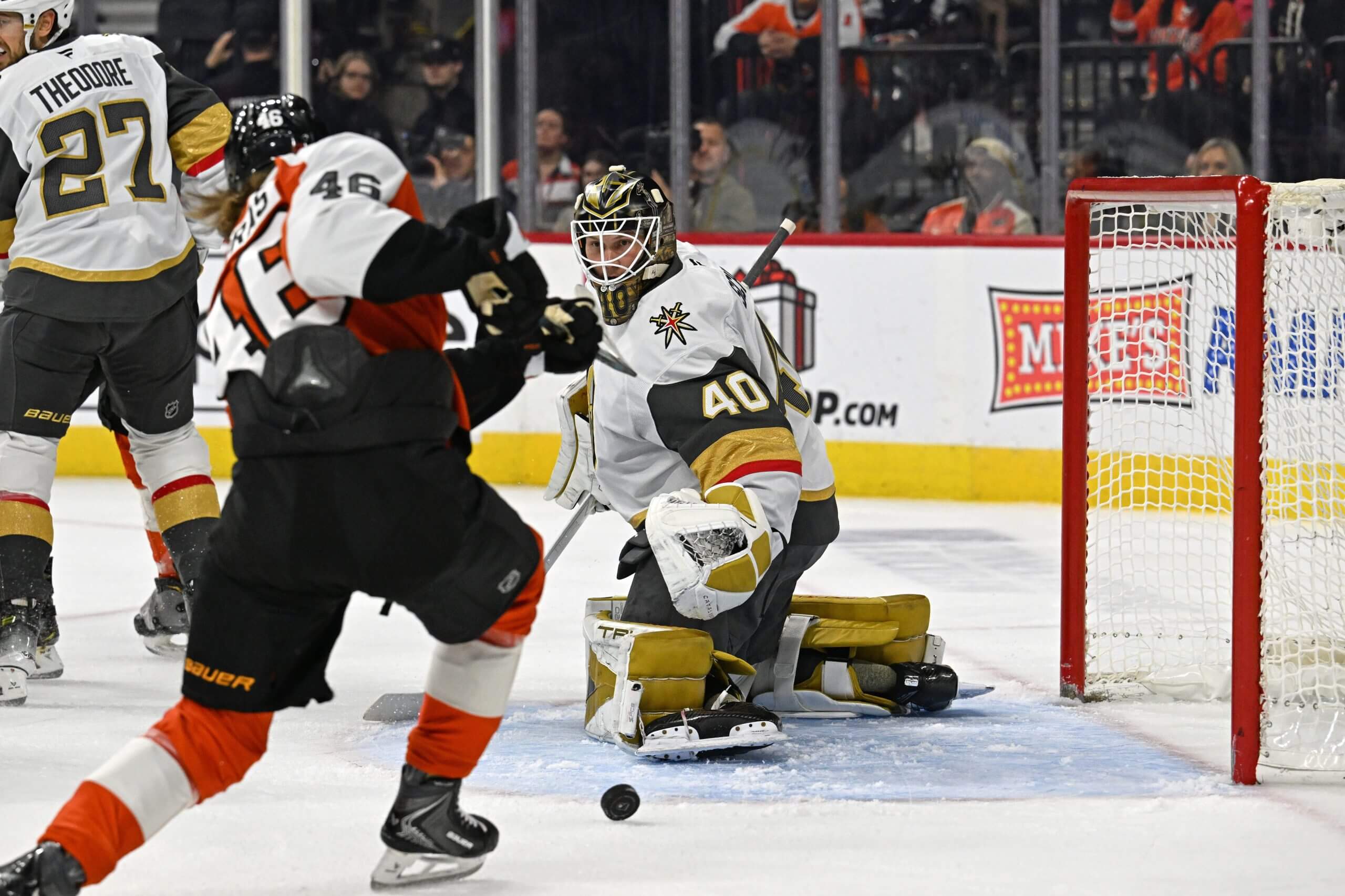 Philadelphia's Trevor Zegras shoots the puck into a gaping net with Vegas goalie Akira Schmid looking over his shoulder.