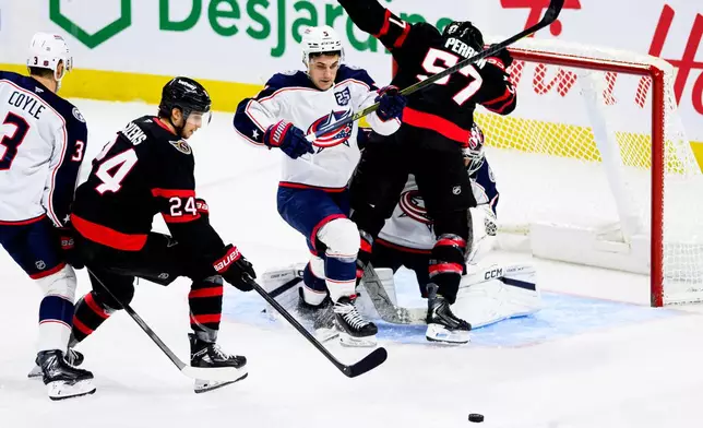 Ottawa Senators' Dylan Cozens (24) battles for possession of the puck against Columbus Blue Jackets' Denton Mateychuk (5) during the third period of an NHL hockey game in Ottawa, Monday, Dec. 29, 2025. (Spencer Colby/The Canadian Press via AP)