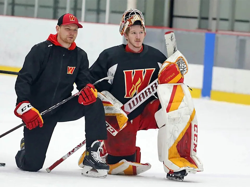 Calgary Wranglers goaltending coach Mackenzie Skapski, left, chats with Dustin Wolf during a break in practice in 2024, when Wolf was developing with the Wranglers.