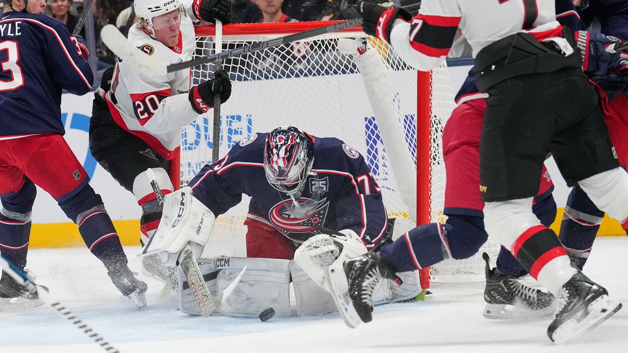 Columbus Blue Jackets goaltender Jet Greaves (73) covers the puck between Ottawa Senators left wing Fabian Zetterlund (20) and left wing Brady Tkachuk (7) in the second period of an NHL hockey game Thursday, Dec. 11, 2025, in Columbus, Ohio. (AP Photo/Sue Ogrocki)