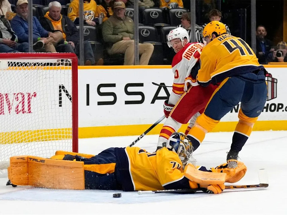 Nashville Predators goaltender Juuse Saros (74) blocks a shot by Calgary Flames left wing Jonathan Huberdeau (10) during the first period of an NHL hockey game Tuesday, Dec. 2, 2025, in Nashville, Tenn.