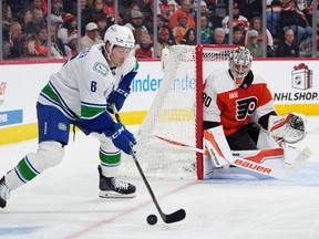 Philadelphia Flyers goaltender Dan Vladar, right, watches as Brock Boeser (6) plays the puck during the first period