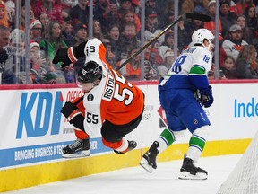 Philadelphia Flyers' Rasmus Ristolainen, left, falls after he was checked into the boards by Vancouver Canucks' Drew O'Connor during the first period