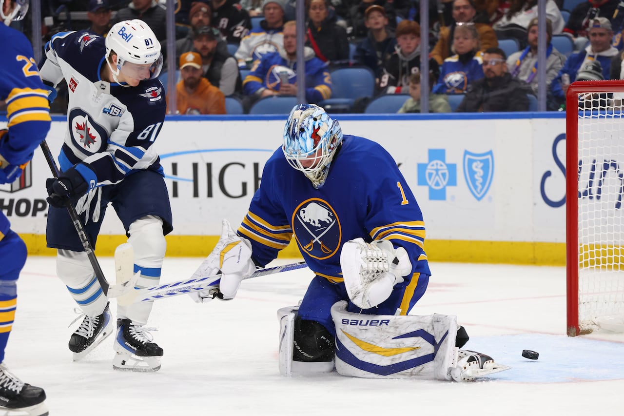 A hockey player puts the puck past the goalie near the crease.