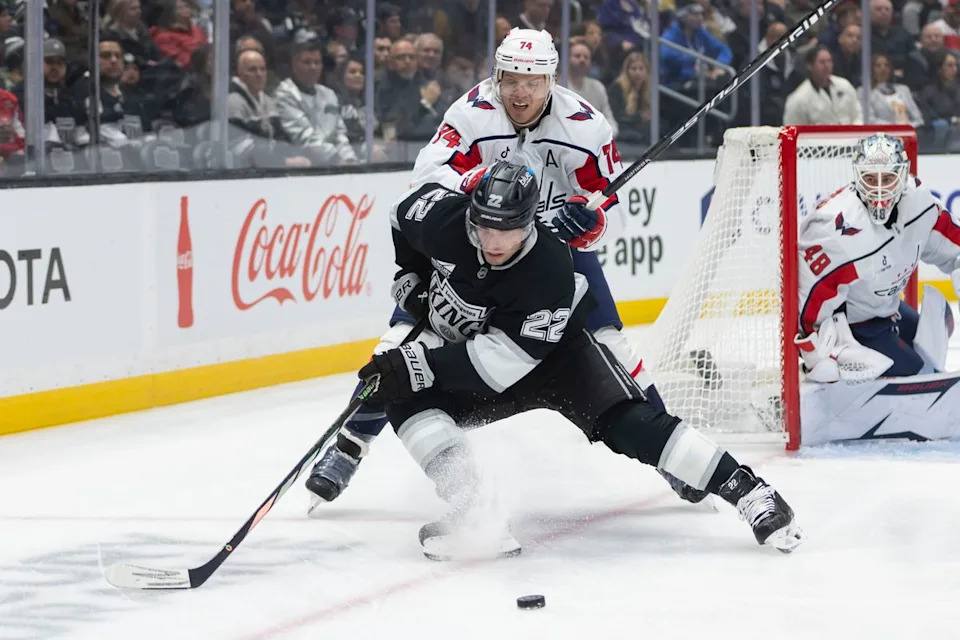 Left wing Kevin Fiala #22 of the Los Angeles Kings reaches for the puck as defenseman John Carlson #74 of the Washington Capitals pushes him during an NHL hockey game, Tuesday December 2, 2025 in Los Angeles, Calif.