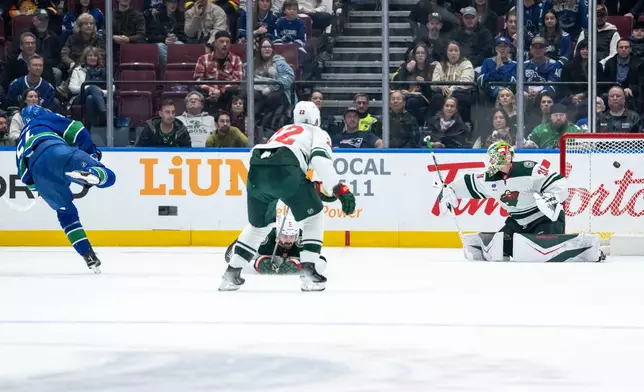 Vancouver Canucks Aatu Raty, left, scores on Minnesota Wild goaltender Jesper Wallstedt (30) during second period NHL hockey action in Vancouver on Saturday, Dec. 6, 2025. (Ethan Cairns/The Canadian Press via AP)